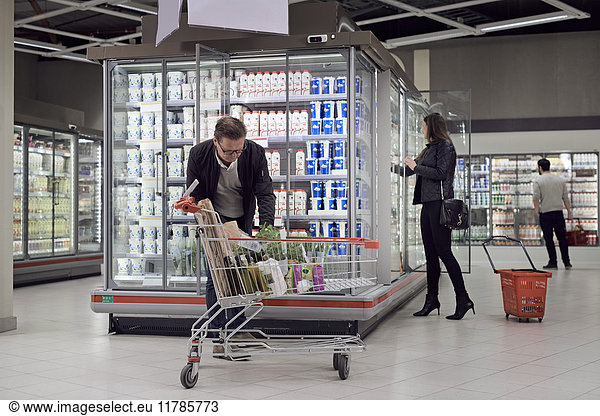 People buying groceries at refrigerated section in supermarket