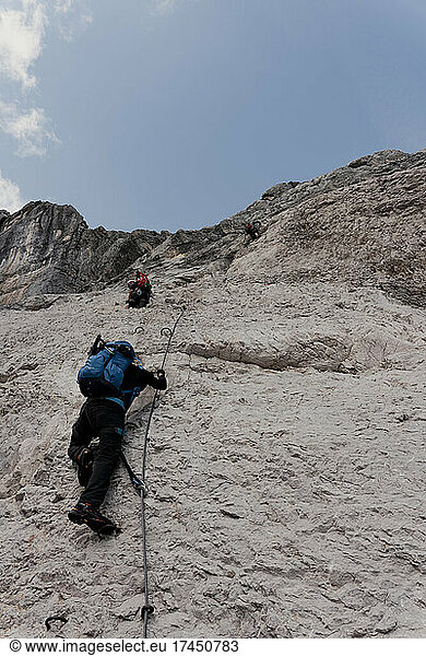 People climbing steep rock wall