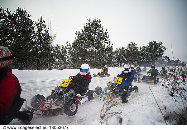 People enjoying go-carts racing on snow covered field