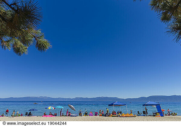 People enjoying the beach and the clear water of Lake Tahoe.