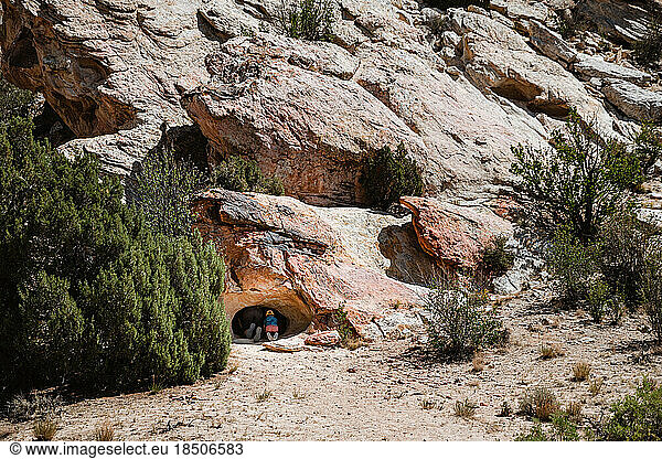 People exploring small cave in Utah desert