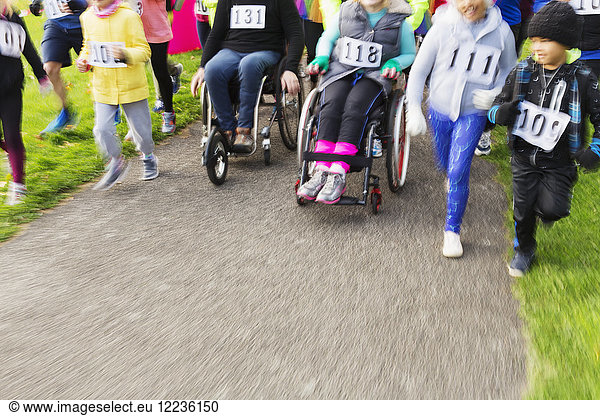 People in wheelchairs and runners moving at charity race