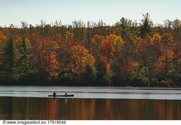 People kayaking in lake by autumn forest