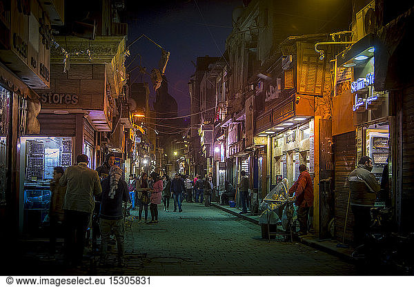 People on illuminated street amidst buildings in Cairo city at night