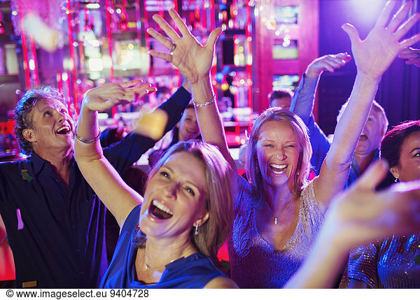 People raising hands and laughing in nightclub