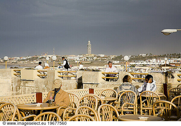 People sitting in a cafe along the beach side Corniche. Casablanca  Morocco.