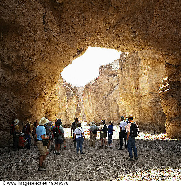 People standing under a natural arch in a desert canyon. Death Valley National Park  California.