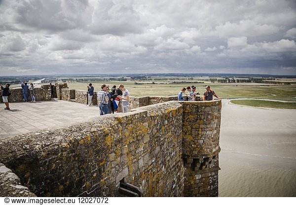 People visiting Mont Saint Michel monastery  Brittany  France enjoying the view from the famous island commune  Le Mont Saint Michel's balcony.