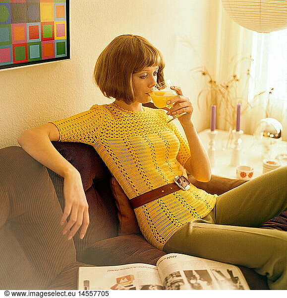 people  women  1960s  woman sitting on a cord sofa and drinking orange juice  half length  fashion  60s  historic  historical  pullover  crocheted  crochet  pageboy style  20th century  female