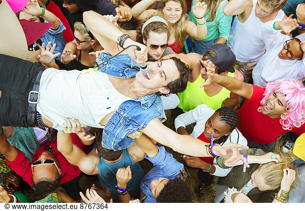 Performer with microphone crowd surfing at music festival