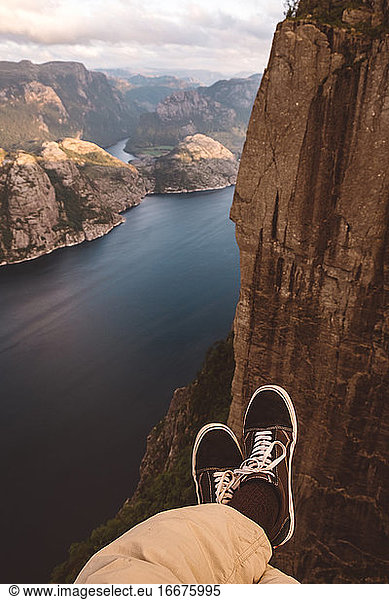 Person cross legged at edge of cliff with a fjords view in Norway