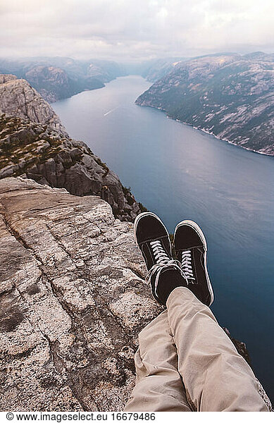Person cross legged at edge of cliff with a fjords view in Norway