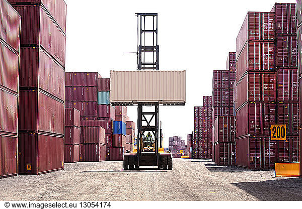 Person driving forklift by cargo containers at commercial dock
