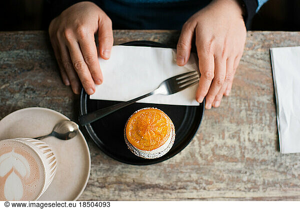 person holding plate with a cake on a plate in a cafe