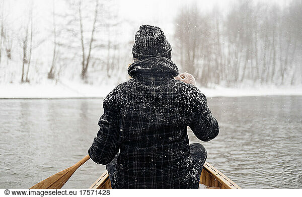 Person in a boat on a snowy river  view from behind