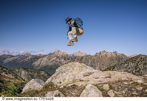 Person jumping high on a cliff in the north cascade mountains