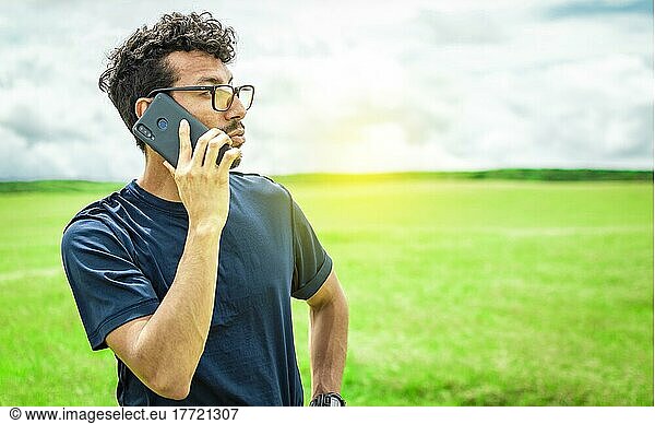 Person mit Handy im Feld beim Telefonieren  Mann beim Telefonieren im Feld  Mann auf einer Straße beim Telefonieren  junge Person beim Telefonieren im Feld