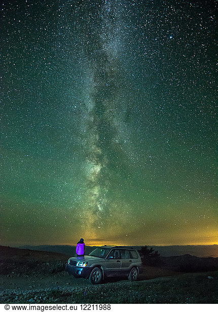 Person sitting on car  looking at view of milky way  rear view  Nickel Plate Provincial Park  Penticton  British Columbia  Canada