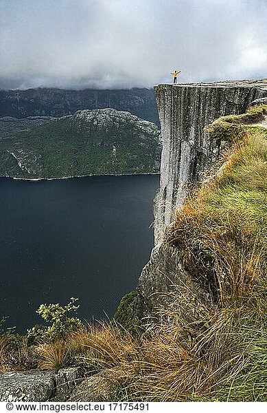 Person steht an steiler Klippe  Felskanzel Preikestolen  Lysefjord  Ryfylke  Rogaland  Norwegen  Europa