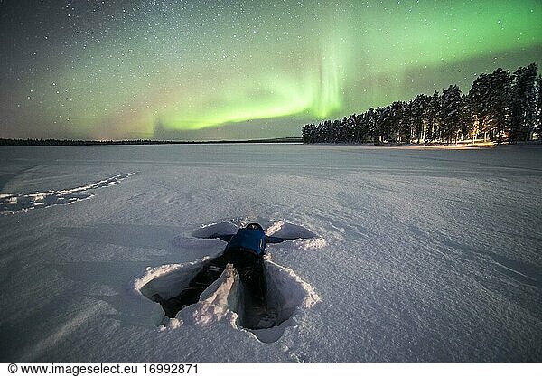 Person unter dem Nordlicht (Aurora Borealis)  einem farbenprächtigen grün-violetten Schauspiel in Finnisch-Lappland  innerhalb des Polarkreises in Finnland