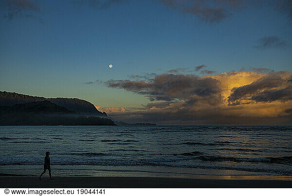 Person walking on Hanalei beach at sunset  Kauai