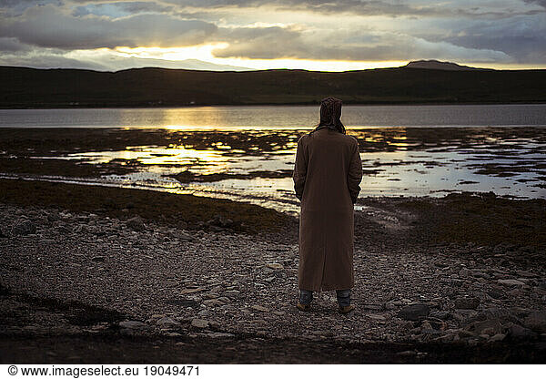 Person watches last light of day set over lake