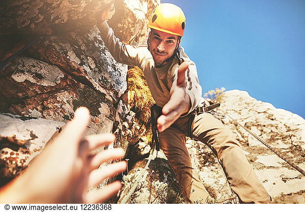 Personal perspective reaching for hand of rock climber