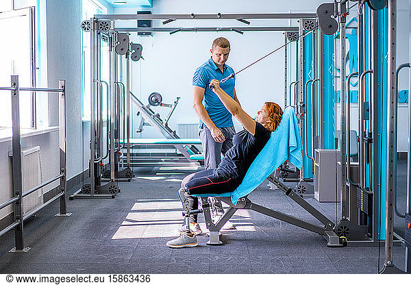 Personal trainer assisting woman with disabilities in her workout