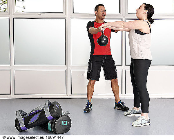 personal trainer helping client at gym in the UK