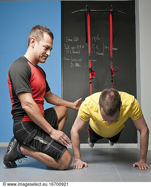 personal trainer helping client with suspension training in gym