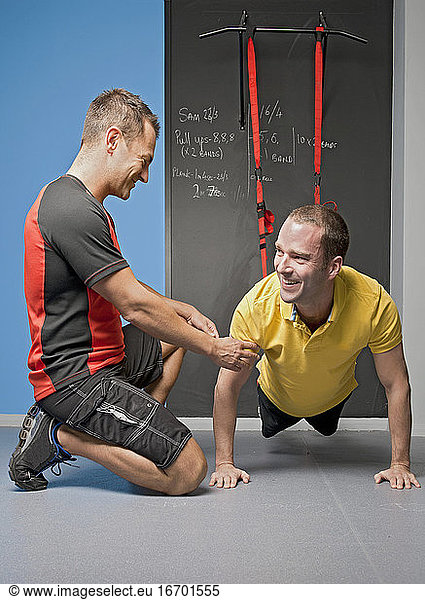 Personal Trainer hilft einem Kunden beim Suspensionstraining im Fitnessstudio