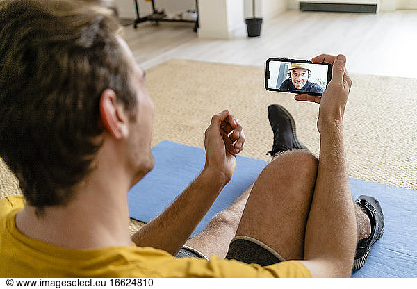 Personal Trainer spricht per Videokonferenz  während er zu Hause sitzt