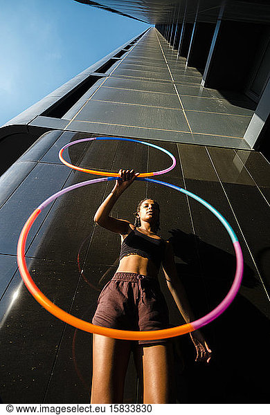 Perspective view of young woman performing Hula Hoop dance in city