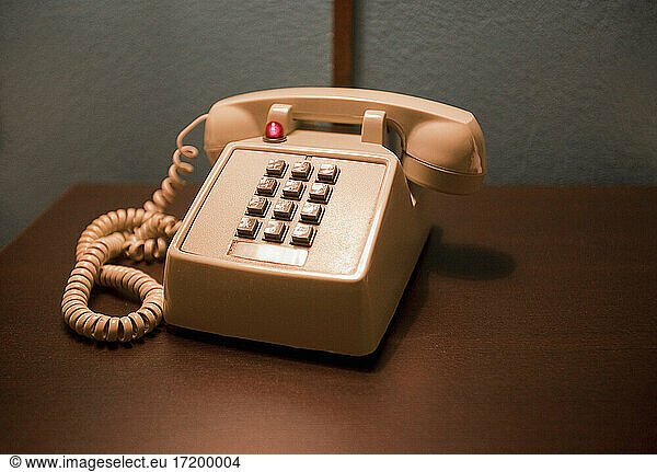 Pfirsichfarbenes Telefon auf Holztisch