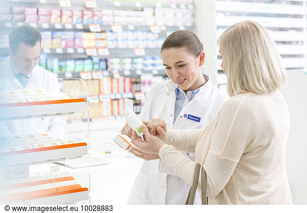 Pharmacist and customer reviewing label on box in pharmacy