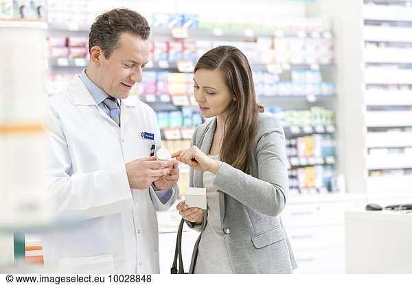 Pharmacist and customer reviewing prescription label in pharmacy
