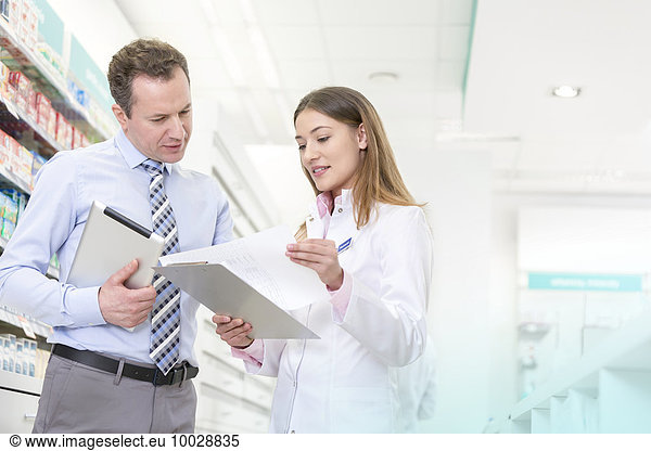 Pharmacist and manager reviewing paperwork in pharmacy