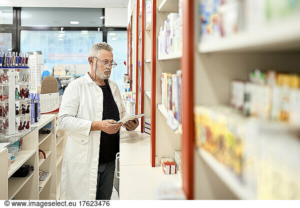Pharmacist holding tablet PC working in pharmacy store