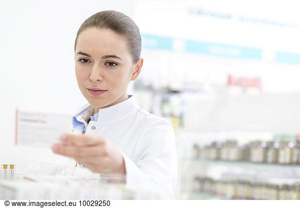 Pharmacist reading label on box in pharmacy