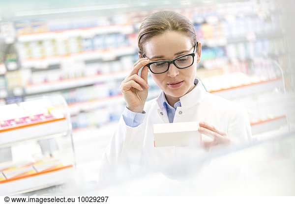 Pharmacist reading label on box in pharmacy
