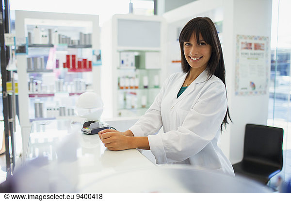 Pharmacist smiling behind counter in drugstore