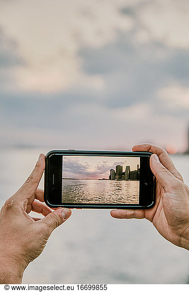 Phone taking picture of new york city skyline at sunset.