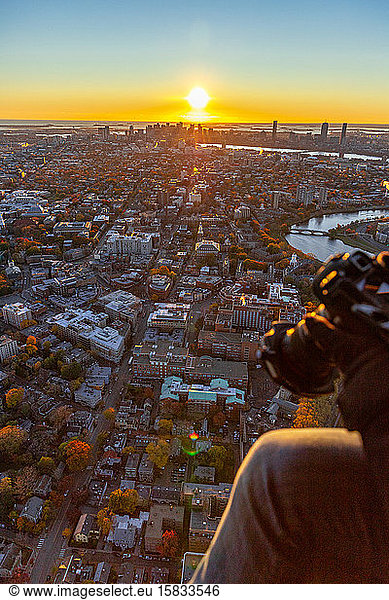 Photographer capturing aerial scenes from helicopter as the sun rises.
