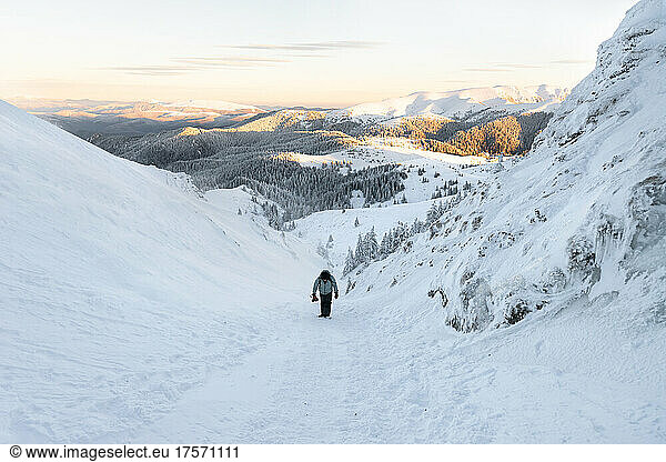 Photographer Hiking on Frozen Landscape at Sunset Holding his Camera