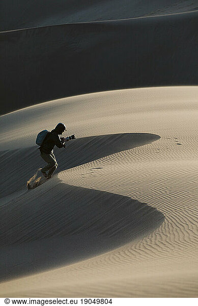 photographer runs up a dune at great sand dunes national park