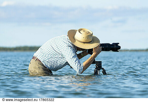 Photographer standing in water taking a photo