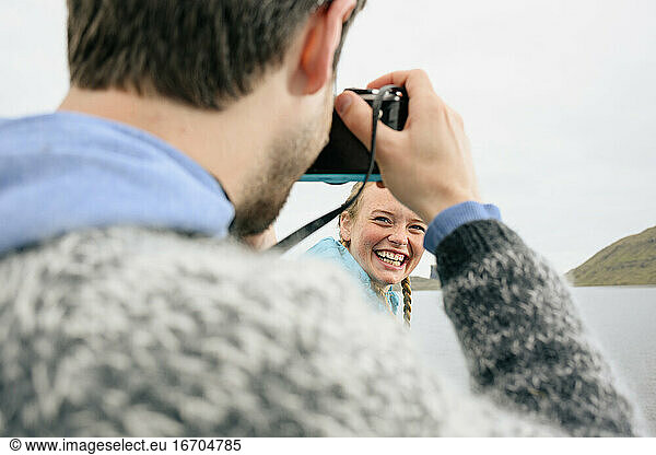 Photographer taking picture of happy woman near sea