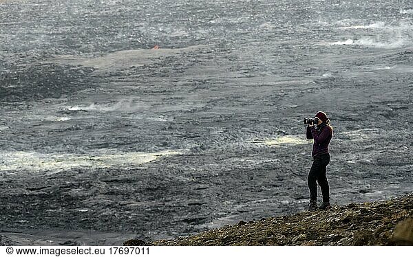 Photographer taking pictures with camera  lava fields in the back  volcanic eruption  active table volcano Fagradalsfjall  Krýsuvík volcano system  Reykjanes Peninsula  Iceland  Europe