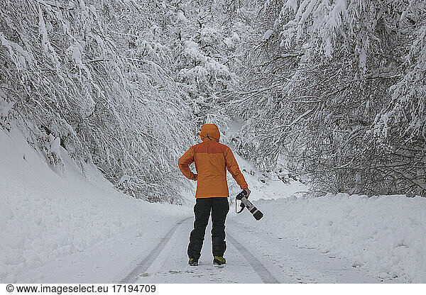 photographer waiting over snowy road in forest