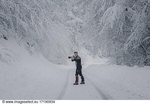 photographer working in snowy road in forest